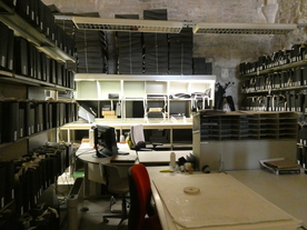 Salle de travail dans un vieux bâtiment avec bureaux, étagères et éclairage au néon. - Agrandir l'image, .JPG 5,2 MB (fenêtre modale)