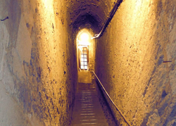 Escalier sombre et étroit, vaguement éclairé par une petite fenêtre poussièreuse à carreaux - Agrandir l'image (fenêtre modale)