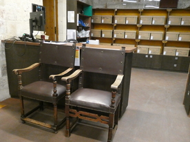 Deux imposants fauteuils anciens en cui avec accoudoirs bois ; en arrière plan, des casiers remplis de boîtes de carton - Agrandir l'image, .JPG 5,1 MB (fenêtre modale)