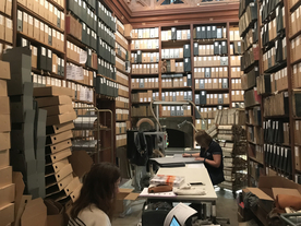 Personnel assurant le conditionnement d'archives dans un ancien magasin avec des rayonnages en bois - Agrandir l'image, .JPG 335,4 KB (fenêtre modale)