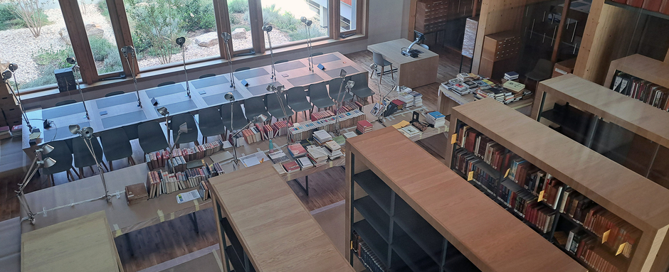 Vue en hauteur sur une salle de lecture équipée de bibliothèques et de bureaux de consultation