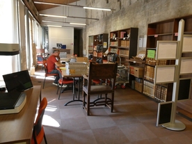 Grande salle de lecture encombrée de mobilier ete de cartons dans un bâtiment médiéval ; un homme travaille sur un ordinateur - Agrandir l'image, .JPG 740,7 KB (fenêtre modale)