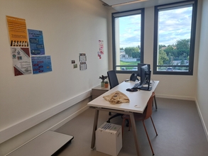 Vue sur un bureau doté d'un équipement informatique, quelques affiches ornent les murs - Agrandir l'image (fenêtre modale)