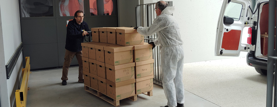 Mise sur palettes de cartons par deux hommes dont un en combinaison de protection